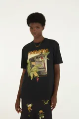 Remera Farm Rio de color negro con cuello redondo y mangas cortas. Presenta un estampado frontal con la inscripción de la marca, un tranvía rodeado de vegetación, animales y elementos tropicales.