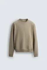 Sudadera de cuello redondo con ajuste regular, confeccionada en tejido de mezcla de algodón con interior de rizo y acabados en rib en cuello, puños y ruedo.