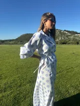 Camisa blanca con lunares celestes, de corte clásico, con cuello camisero y mangas largas abullonadas.