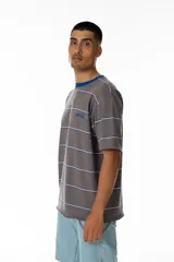 Remera gris a rayas horizontales blancas y azules, con cuello redondo azul y logo 'Vernal' bordado en azul. Corte holgado.