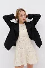 Chaqueta negra de corte relajado confeccionada en mezcla de algodón y lyocell, con solapas anchas redondeadas, hombros caídos, botonadura frontal y bolsillos delanteros de parche.