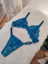 Conjunto de lencería de encaje floral color verde petróleo, compuesto por un corpiño triangular sin aro y una bombacha tipo colaless con tiras laterales ajustables.