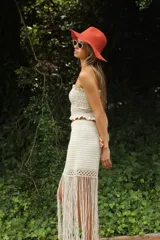 Falda tejida a mano en crochet, color crudo, con flecos en el ruedo y abertura lateral.