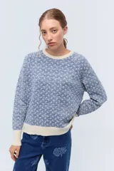 Sweater color crudo con jacquard floreado en lurex negro y puños con textura delicada.