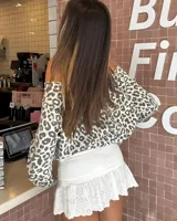 Minifalda short blanca de tiro alto, con cintura fruncida y vuelo inferior con detalles de bordado inglés y encaje calado.