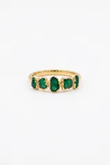 Anillo de diseño irregular en tono dorado con cinco piedras verdes engarzadas de forma orgánica.
