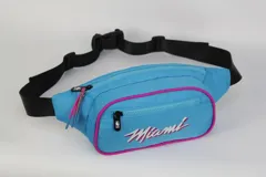 Riñonera celeste de nylon con contorno fucsia, cierre doble y correa regulable negra. Estampado frontal con el nombre "Miami" en cursiva y el logo de la NBA.