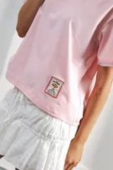 Remera de algodón color azul marino, corte relajado con hombro caído. Presenta cuello redondo blanco y bordado a mano en contraste en los puños de las mangas. Tiene un parche bordado en la parte inferior del frente.