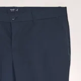Pantalón de vestir de corte slim en color azul marino, con cierre de botón y cremallera, trabillas para cinturón y bolsillos laterales.