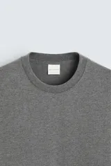 Camiseta de corte regular confeccionada en tejido de algodón compacto, con cuello redondo y manga corta.
