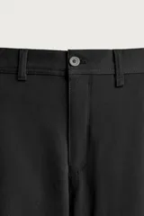 Pantalón chino negro slim fit de corte recto, con bolsillos frontales, trabillas para cinturón y cierre frontal con cremallera y botón.