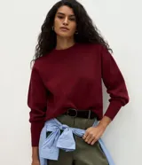 Buzo de tricot con cuello redondo y puños ajustados. Presenta un diseño de calce holgado y tejido de punto liso.