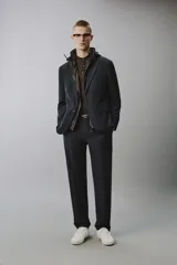 Blazer de corte regular fit confeccionado en tejido técnico y transpirable de color negro, con cuello de solapas de muesca, cierre frontal de un botón y bolsillos con solapa en la cadera.