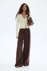 Pantalón culotte marrón chocolate de tiro alto con cintura elástica y lazo para atar. Piernas anchas con bolsillos laterales y un bolsillo decorativo en la parte trasera.