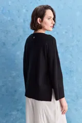 Sweater blanco de punto con diseño holgado, cuello redondo, mangas largas acampanadas y detalles de textura horizontal en el tejido.
