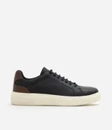 Championes casuales para hombre confeccionados en cuero negro, con diseño minimalista de caña baja, detalles en color marrón en el talón, cordones elásticos y suela alta de goma en tono off-white.