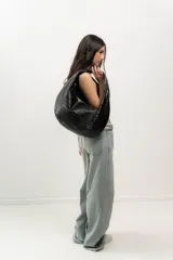 Bolso hobo negro de cuero con textura tipo cocodrilo, con asa anudada al hombro.