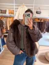 Campera puffer oversize color marrón, con paneles frontales y traseros de pelo sintético suave. Presenta mangas acolchadas, cierre frontal y bolsillo con cierre en la manga.