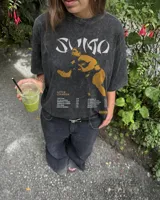 Remera oversize color beige con cuello redondo y diseño gráfico impreso en el frente, que incluye la silueta de un luchador de sumo y tipografía alusiva.