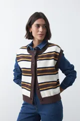 Chaleco tejido de punto con diseño a rayas horizontales en tonos crema, marrón y mostaza. Presenta cuello redondo, cierre frontal con botones y terminaciones acanaladas.