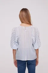 Blusa blanca con rayas verticales celestes, mangas abullonadas y detalles de calado en los hombros y el frente.