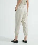 Pantalón jogger Marfinno color beige, confeccionado en suedine con cintura elástica y cordón ajustable. Presenta detalles perforados en los bolsillos laterales y en las costuras laterales, además de puños elásticos en los tobillos.
