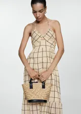 Vestido largo de algodón con estampado de cuadros oscuros sobre fondo beige. Presenta diseño evasé, cuello halter con tirantes finos y detalle de panel nido de abeja en la parte superior.
