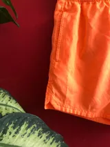 Short de baño naranja con cintura elástica ajustable con cordón, bolsillos laterales y logo de la marca Reef en la pierna derecha.
