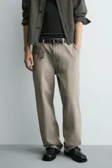 Pantalón de corte relajado confeccionado en tejido de algodón con efecto lavado. Presenta diseño de cinco bolsillos, cierre frontal con cremallera y botón, y detalles de estampados a contraste en la parte delantera y trasera.