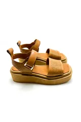 Sandalia de cuero vacuno color camel con plataforma corrida. La capellada ajusta en el empeine con sistema de velcro y tiene un tirador decorativo en el talón.