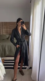 Tapado largo estilo trench de cuero ovino negro, con silueta recta, solapa amplia y cierre frontal cruzado ajustable con lazo en la cintura. Cuenta con bolsillos laterales funcionales y largo midi por debajo de la rodilla.