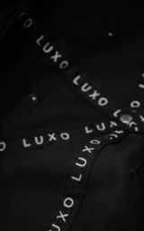 Gorra negra de estilo 5 paneles, con tejido acolchado o con costuras horizontales y visera plana. Presenta un pequeño parche cuadrado negro con un logo blanco bordado en forma de 'X' o lazo.