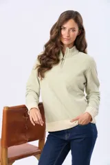 Buzo tejido combinado de color beige, con cuello alto, medio cierre metálico y puños y ruedo acanalados en tono tostado.