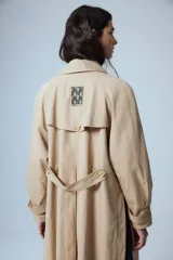 Trench midi color camel confeccionado en algodón y nylon repelente al agua, con cuello clásico, cierre frontal con un botón, bolsillos laterales y tajos laterales. Tiene etiqueta RENÉE en la espalda.