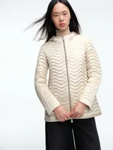 Campera acolchada color beige con diseño de ondas horizontales, cierre frontal completo, capucha integrada y mangas largas.