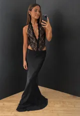 Body de encaje negro con escote profundo en V y diseño sin mangas. Presenta una estructura tipo corset con transparencias y cierre frontal.