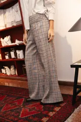 Pantalon de vestir de corte ancho y tiro alto, con cintura elástica fruncida. Presenta un diseño de estampado a cuadros en tonos grises y líneas finas en color naranja.