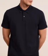 Remera polo de manga corta color verde militar, confeccionada en algodón peruano con cuello convencional y cierre de botones.