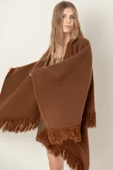 Ruana de lana color beige, tejida en punto acanalado con terminación de flecos en los bordes.