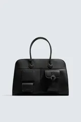 Bolso de viaje negro con acabado grabado y diseño de múltiples bolsillos frontales. Dispone de un compartimento principal con cierre magnético, un bolsillo interno con cremallera y tres bolsillos exteriores de diversos tamaños con cierre de imán. Incluye dos asas de mano superiores.