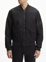 Campera bomber negra Calvin Klein de satén de nailon reciclado, con cuello, puños y bajo de punto de canalé. Tiene cierre de cremallera, bolsillos de hendidura en la cintura, detalle de cremallera en la manga e insignia con el logo de goma de Calvin Klein en la manga. El forro y el relleno son de poliéster reciclado REPREVE®.