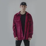 Camisa color borgoña de pana con corte oversize, cuello clásico, cierre con botones, dos bolsillos frontales con botón y mangas largas con puños abotonados.