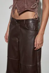 Bermuda de cuerina color marrón oscuro, de corte ancho y largo por debajo de las rodillas, con diseño de tiro medio y costuras horizontales en las piernas.