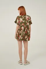 Vestido corto de viscosa con estampado floral en tonos verdes, rojos y blancos. Presenta un diseño holgado con cuello a la base y mangas cortas con volados en los extremos.