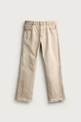 Jeans flare fit de tiro medio confeccionados en denim de algodón color beige, con cinco bolsillos, efecto salpicaduras y bajo irregular.