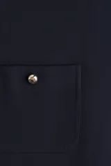 Vestido corto azul marino, de corte recto y sin mangas, con escote redondo y cierre oculto en la espalda. Tiene cuatro bolsillos de parche con botón dorado. Está forrado.