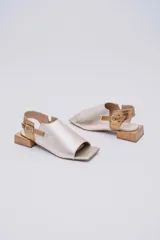 Sandalias de cuero color marrón con puntera abierta, talón descubierto y tira trasera con hebilla. Taco bajo de madera.