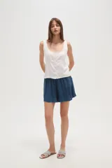 Musculosa blanca de viscosa con escote redondo, cierre frontal con botones y detalles bordados en los hombros.