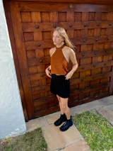 Top halter confeccionado en cuero color camel, con diseño sin mangas, espalda descubierta y ajuste mediante tiras.