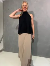 Musculosa negra sin mangas con cuello halter fruncido, confeccionada en tejido liviano de caída fluida.